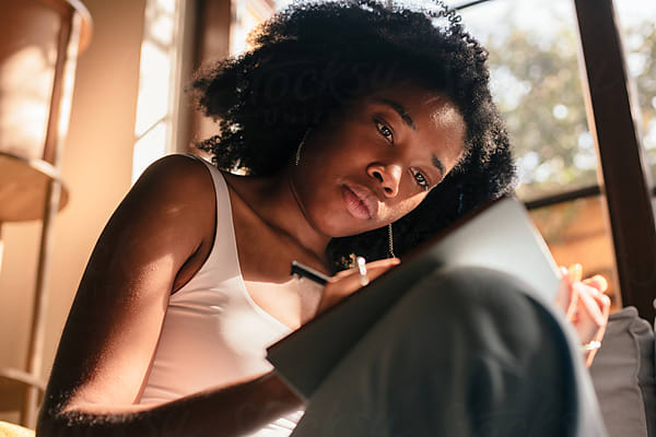 Two young women sit together in conversation, one taking notes