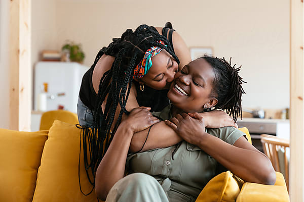 Two women embrace and laugh together at home