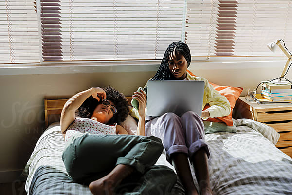 Two teens relax at home with a laptop