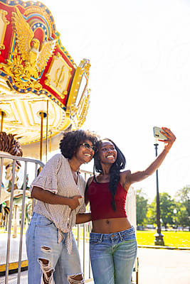 A mother and teenage daughter take a photo together at a fair