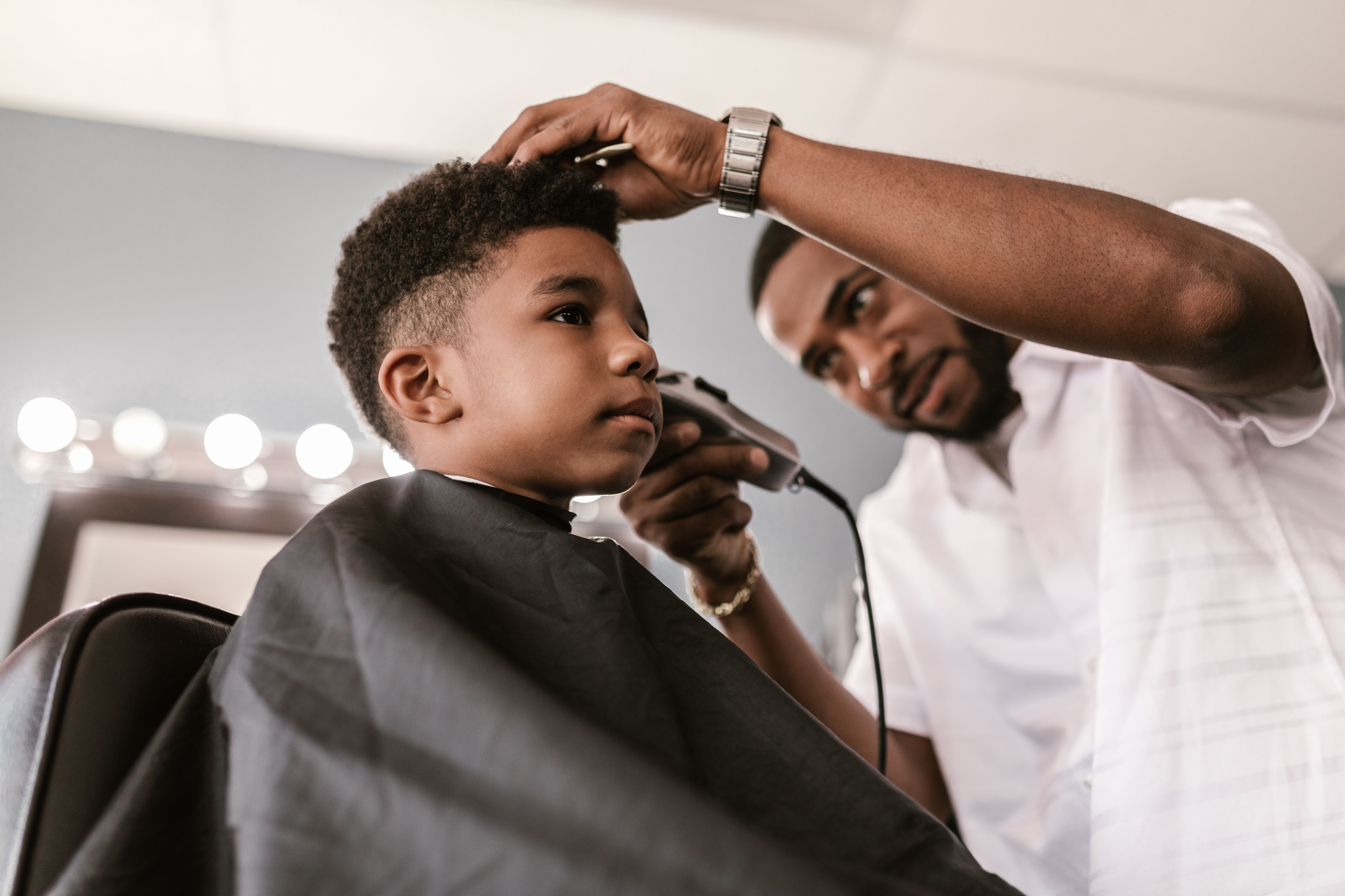 A barber lines up a young boy's haircut in a neighborhood barbershop