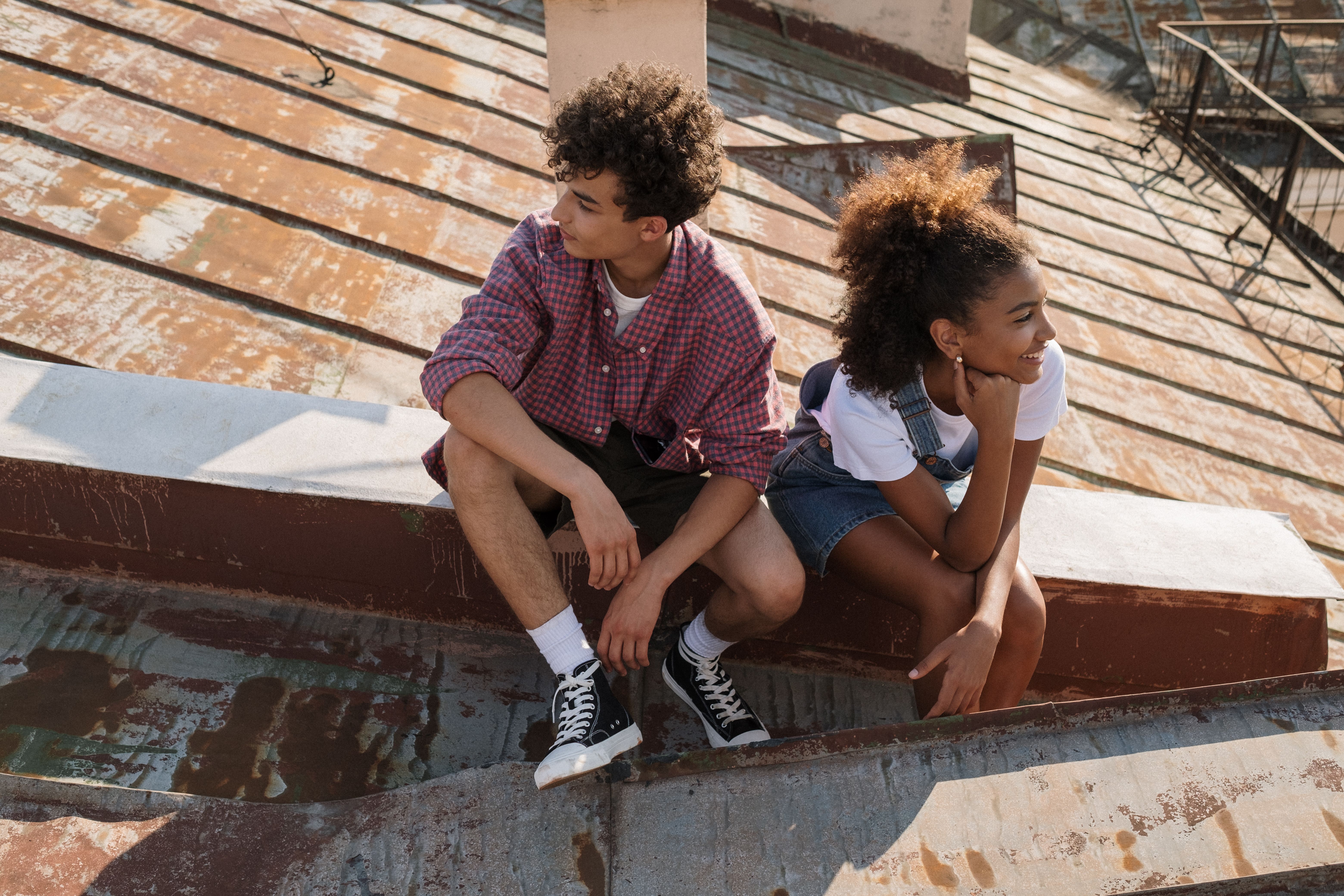 Two teenagers sit together on sunlit steps, talking